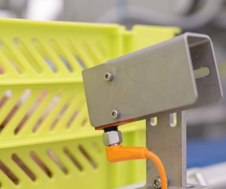 Sensor de identificación de cajas amarillas instalado en el final de línea de clasificación automática de una planta cárnica